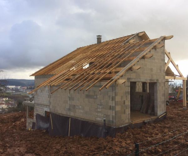 Pose de la charpente en bois sur une maison en construction à Montboucons