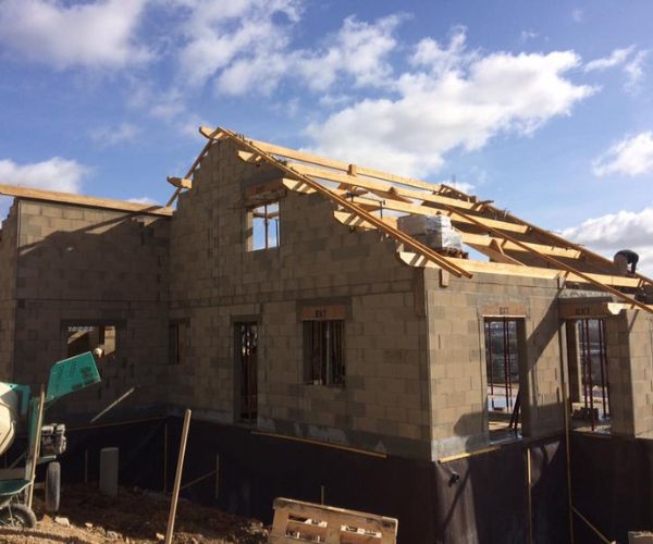 Montage des murs porteurs en blocs béton pour une maison neuve à Montboucons