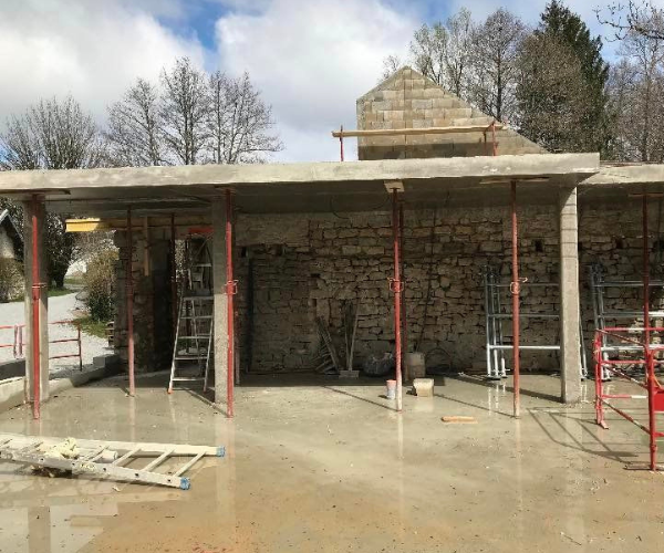 Dalle béton de l’extension accolée à un mur en pierre à La Vèze