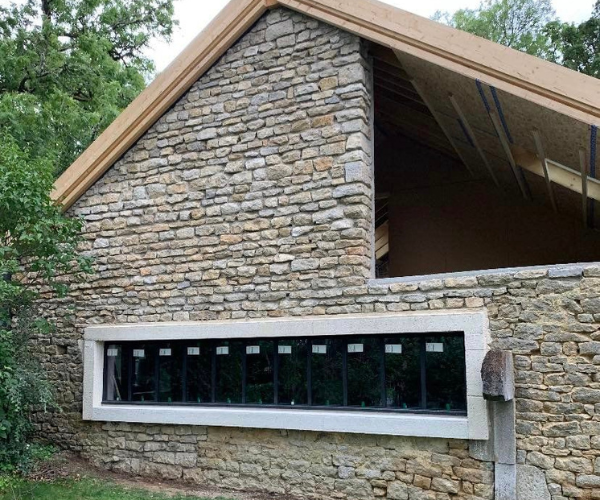 Façade en pierre rénovée avec grande ouverture panoramique à La Vèze