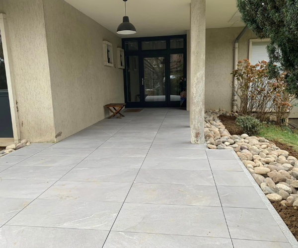 Terrasse d’entrée carrelée avec bordures granit devant une maison à Besançon