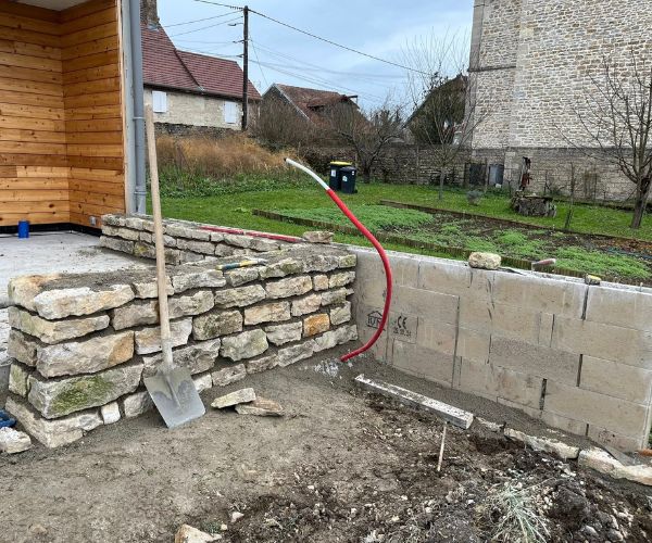 Mur préfabriqué en cours de montage avant parement pierre à Quingey.