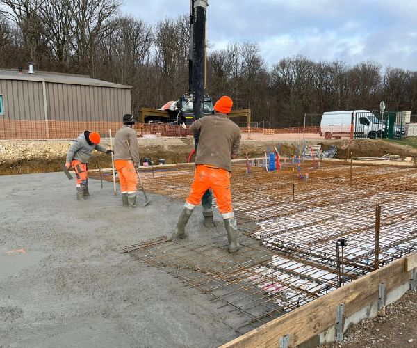 Équipe en train de couler la dalle béton du bâtiment à Perrouse.