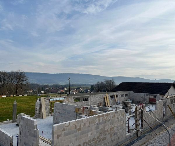 Élévation des murs en blocs béton pour la construction des vestiaires de foot à Perrouse.