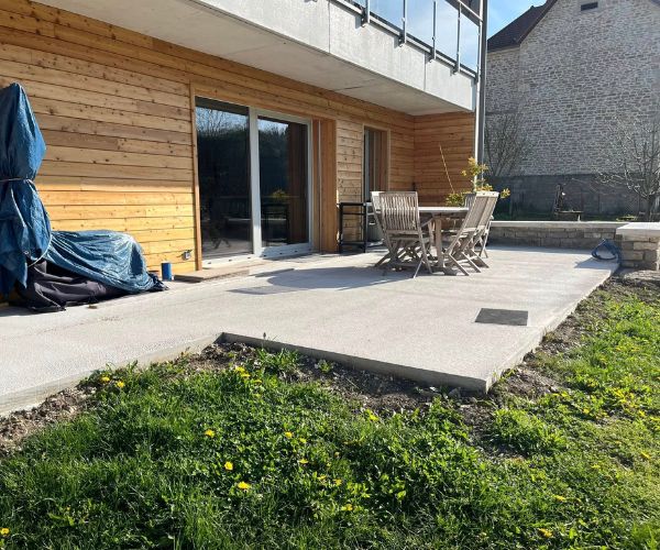 Terrasse en dallage béton autour d’une maison à Quingey.