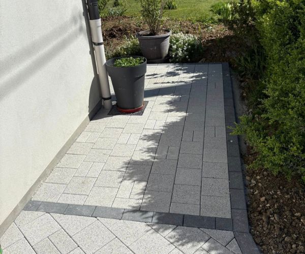 Vue d’ensemble d’un aménagement en pavés Birkenmeier avec mur en blocs Bi Muro à Trepot.